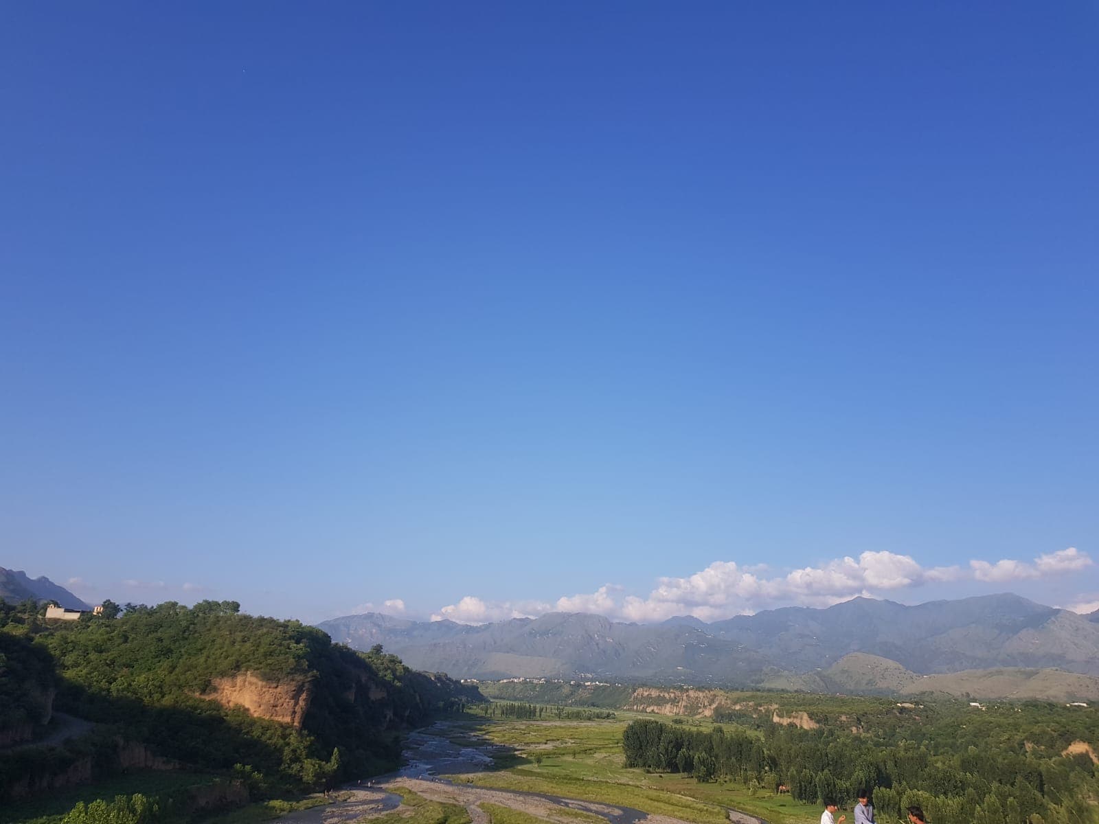 A wide mountain landscape under a clear blue sky.